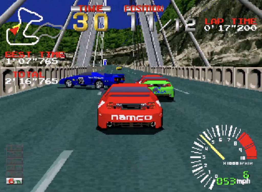 Ridge Racer theres a blue car turned almost crashing with a green race car to the right of it and the player is in a red car.